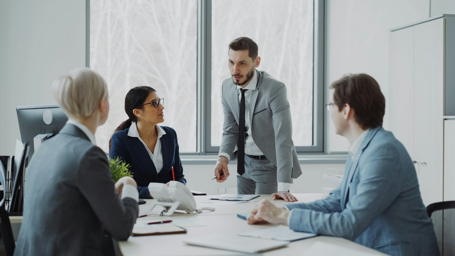 Leader standing at the meeting table listening to the team