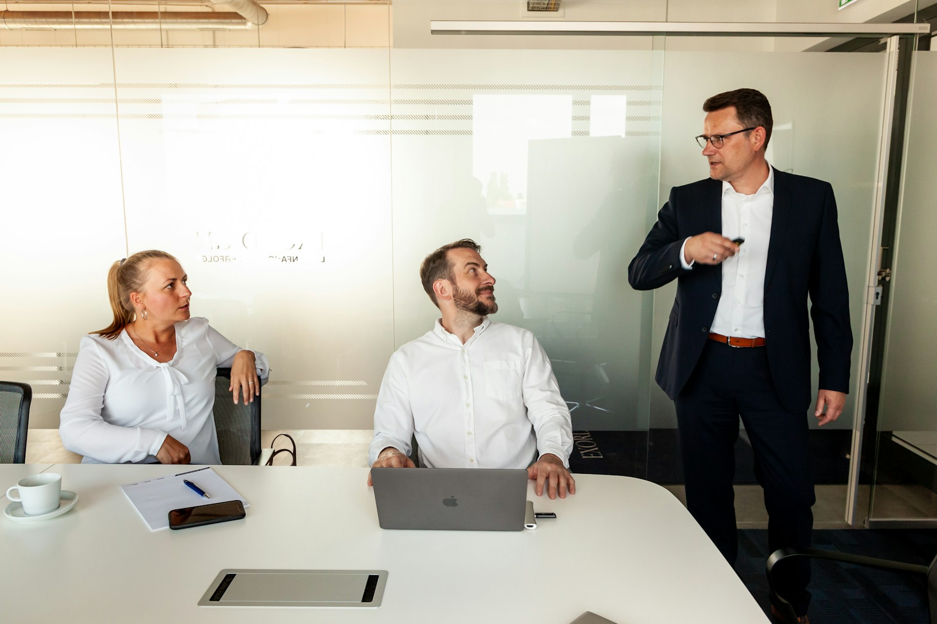 Führungskraft spricht stehend zu ihrem Team im Besprechungsraum